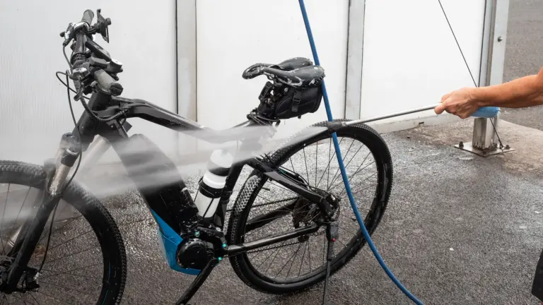 Ein E-Bike wird mit einem Hochdruckreiniger gereinigt, während Wasserstrahlen auf das Fahrrad gerichtet sind.