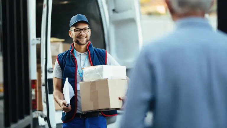 Ein Lieferdienstmitarbeiter trägt mehrere Pakete und steht vor einem Lieferwagen.