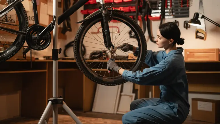 Eine Frau arbeitet an einem Fahrrad, während sie das Hinterrad mit einem Werkzeug anfasst.